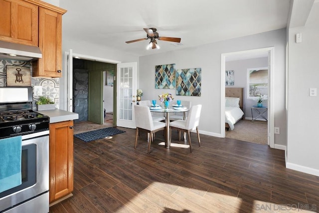 kitchen with french doors, stainless steel gas stove, dark hardwood / wood-style floors, ceiling fan, and decorative backsplash