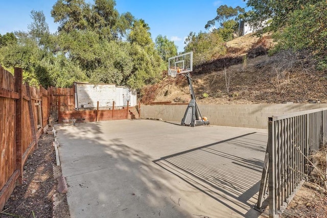 view of patio / terrace with basketball hoop and a storage unit