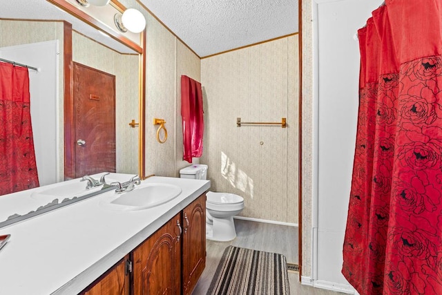 bathroom with hardwood / wood-style flooring, vanity, toilet, crown molding, and a textured ceiling