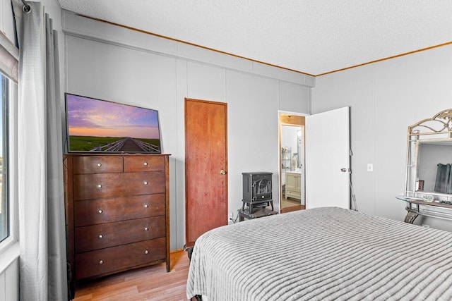 bedroom featuring a wood stove, a textured ceiling, and light hardwood / wood-style floors