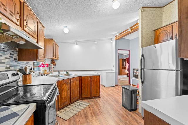 kitchen featuring sink, light hardwood / wood-style flooring, appliances with stainless steel finishes, a textured ceiling, and decorative backsplash