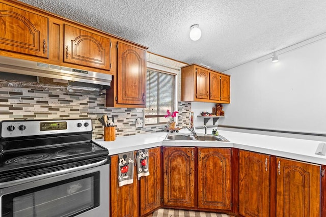 kitchen featuring sink, stainless steel range with electric cooktop, rail lighting, and a textured ceiling