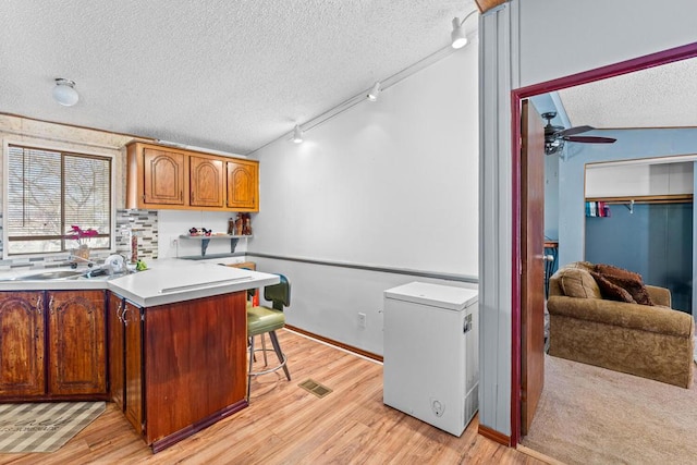 kitchen with fridge, track lighting, kitchen peninsula, and a textured ceiling