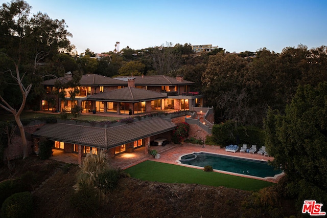 back house at dusk with a patio and a balcony