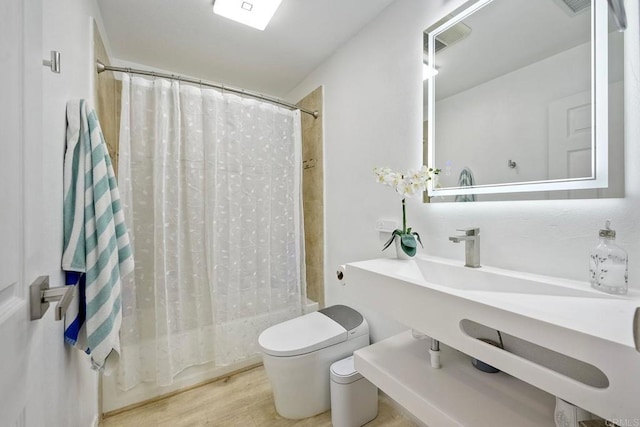 bathroom featuring shower / tub combo, hardwood / wood-style floors, and toilet