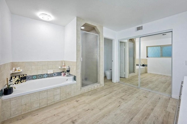 bathroom with hardwood / wood-style flooring, plus walk in shower, and toilet