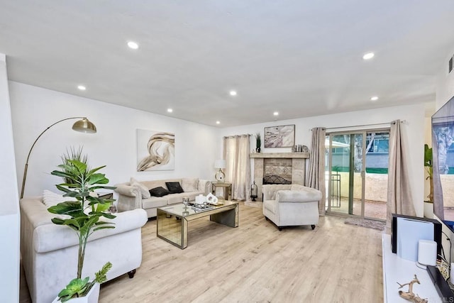 living area with recessed lighting, light wood-style flooring, and a fireplace