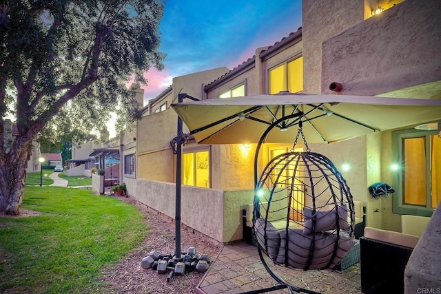 property exterior at dusk featuring a lawn and stucco siding