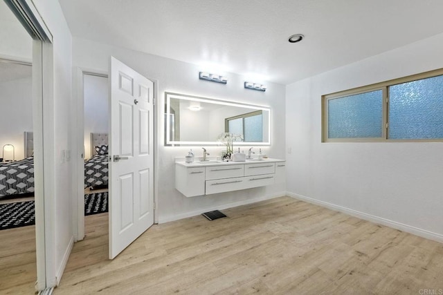 full bathroom featuring double vanity, wood finished floors, baseboards, and ensuite bathroom