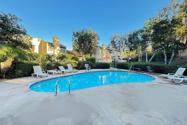 community pool with a patio and fence