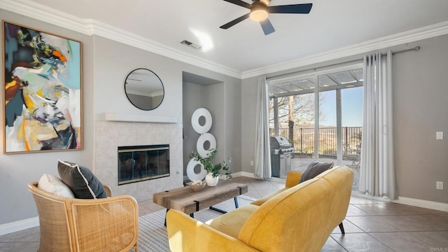 tiled living room with a fireplace, ornamental molding, and ceiling fan