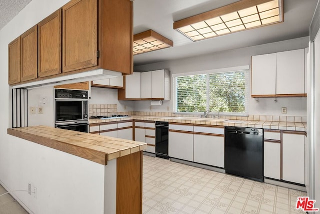 kitchen featuring sink, black appliances, white cabinets, tile countertops, and kitchen peninsula