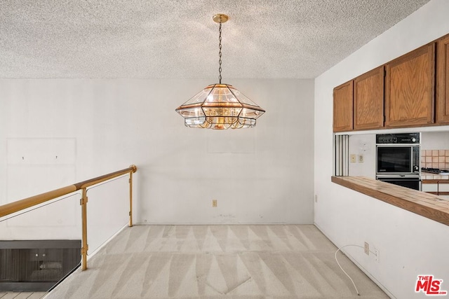 unfurnished dining area featuring light colored carpet and a textured ceiling