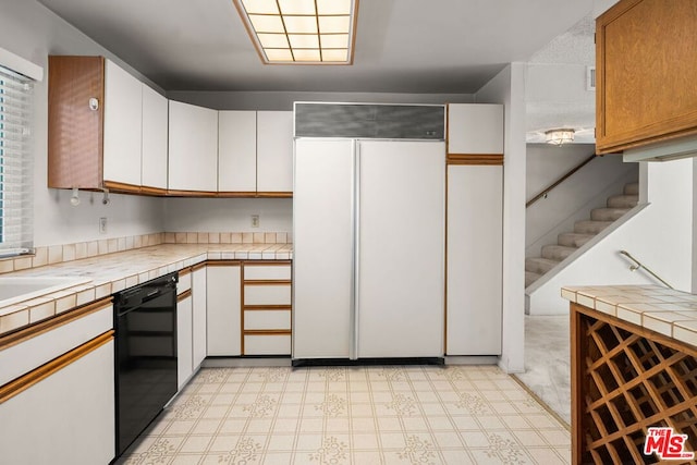 kitchen featuring dishwasher, tile countertops, paneled built in fridge, and white cabinets