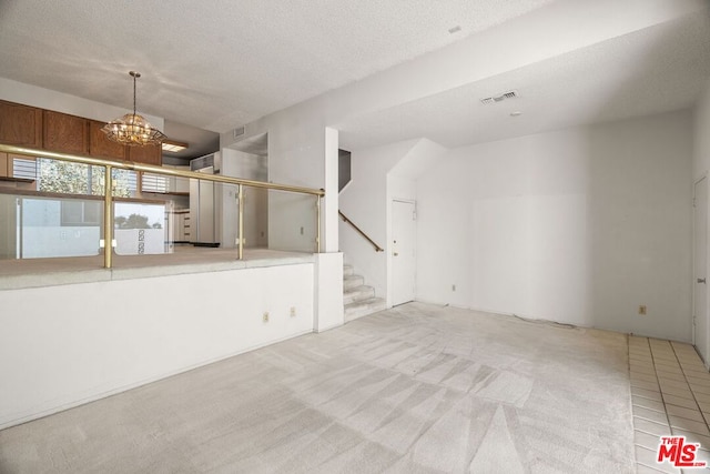 unfurnished living room featuring light carpet, a notable chandelier, and a textured ceiling