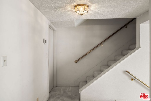 stairs featuring carpet floors and a textured ceiling