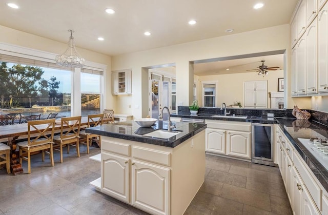 kitchen featuring wine cooler, sink, a kitchen island with sink, and kitchen peninsula