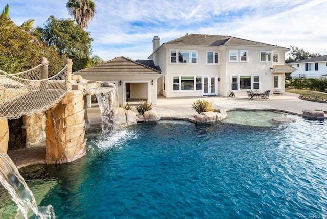 rear view of house featuring a patio, pool water feature, and french doors