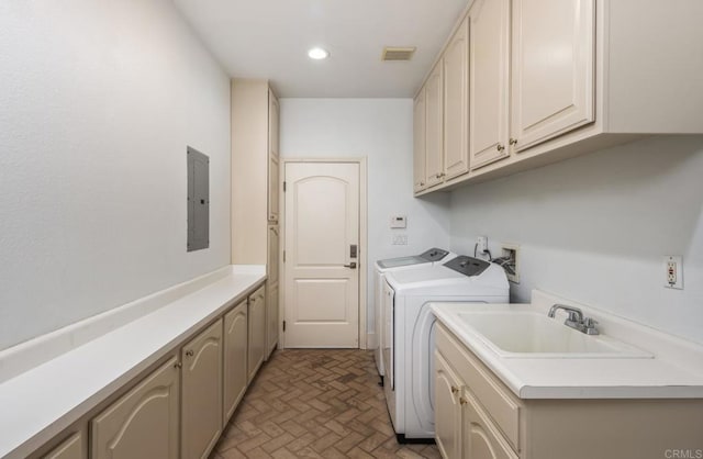 clothes washing area with cabinets, washing machine and dryer, sink, and electric panel