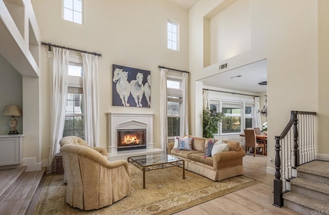 living room with a towering ceiling, wood-type flooring, and a healthy amount of sunlight