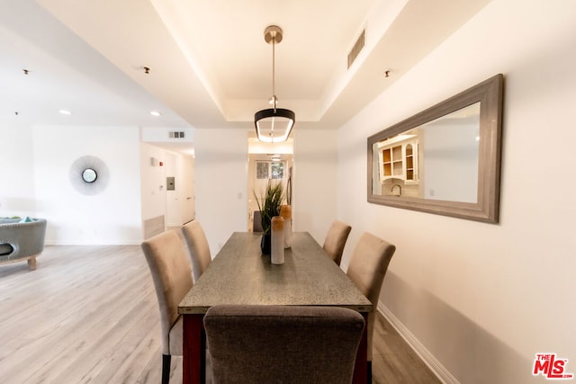 dining space with a tray ceiling and hardwood / wood-style floors