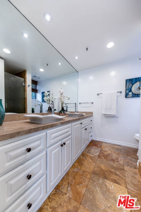 bathroom with vanity, a shower with door, and toilet