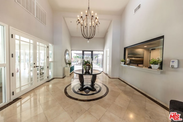 foyer featuring french doors, a towering ceiling, and a chandelier