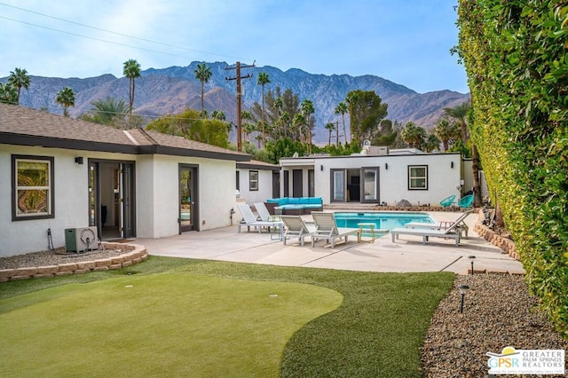 rear view of property featuring a patio, a mountain view, and outdoor lounge area