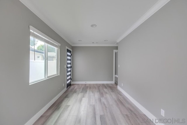 empty room with crown molding and light hardwood / wood-style flooring