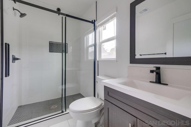 bathroom featuring vanity, a shower with door, tile patterned floors, and toilet