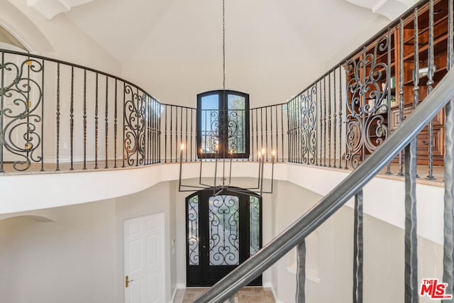 stairway featuring a towering ceiling and a notable chandelier