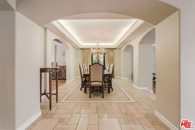 dining space with a chandelier and a raised ceiling