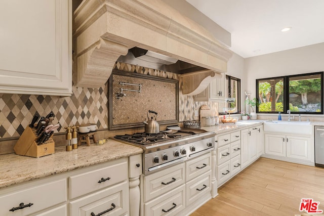 kitchen featuring sink, appliances with stainless steel finishes, light stone countertops, custom range hood, and decorative backsplash