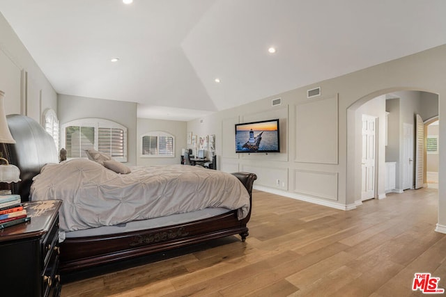 bedroom featuring multiple windows, vaulted ceiling, and light hardwood / wood-style flooring