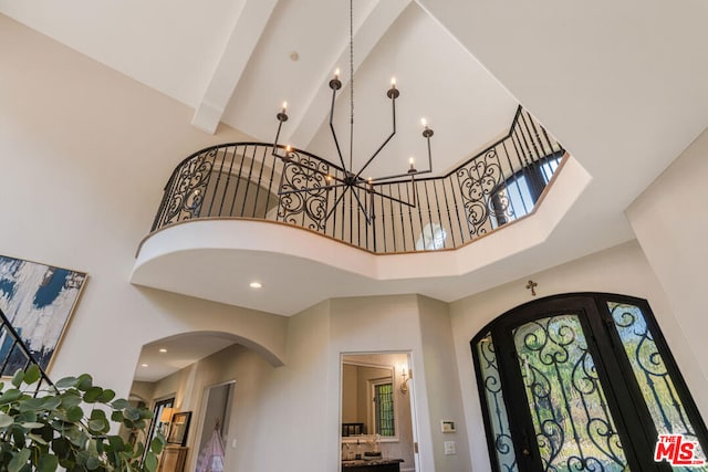 entryway featuring a high ceiling, a notable chandelier, beam ceiling, and french doors