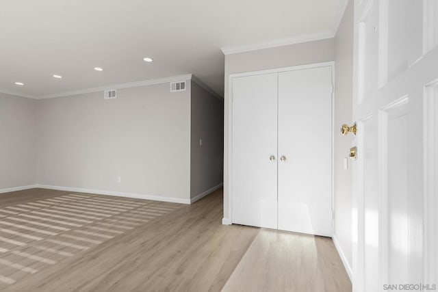 empty room with crown molding and light hardwood / wood-style floors