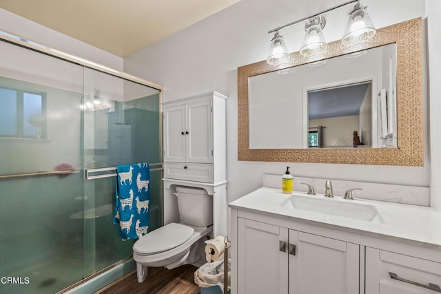 bathroom featuring vanity, wood-type flooring, a shower with shower door, and toilet