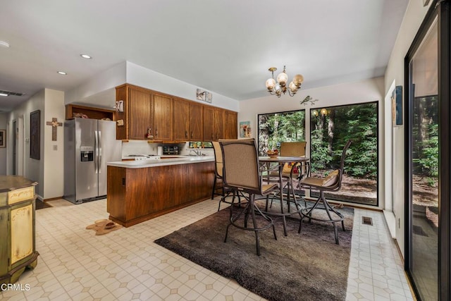 kitchen with stainless steel refrigerator with ice dispenser, sink, kitchen peninsula, and an inviting chandelier