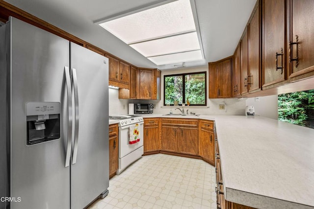 kitchen featuring stainless steel fridge, sink, and electric range