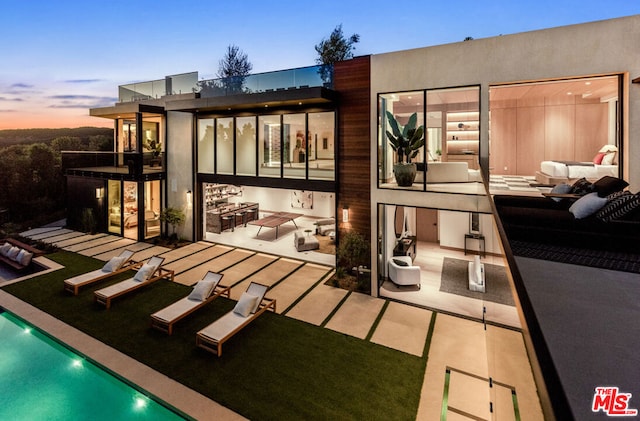 back house at dusk featuring an outdoor living space and a patio area