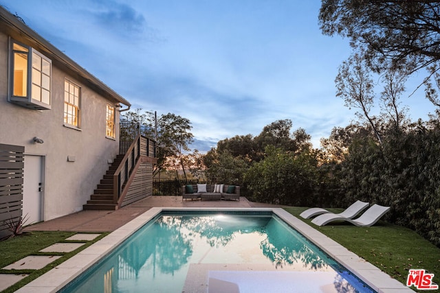 pool at dusk with an outdoor living space