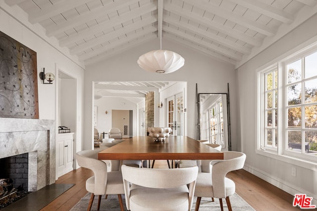 dining space featuring wood ceiling, wood-type flooring, a premium fireplace, and vaulted ceiling with beams