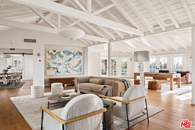 living room with hardwood / wood-style floors, beam ceiling, high vaulted ceiling, french doors, and a barn door