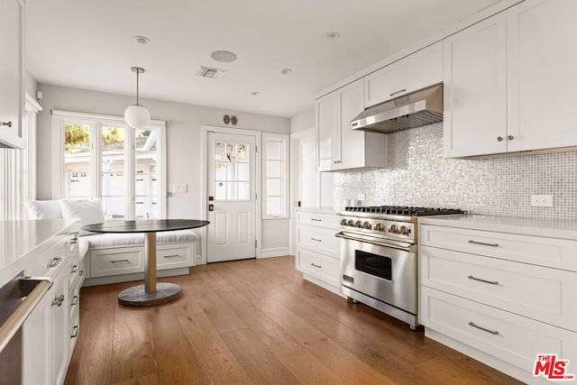 kitchen featuring premium range, pendant lighting, backsplash, white cabinets, and light wood-type flooring