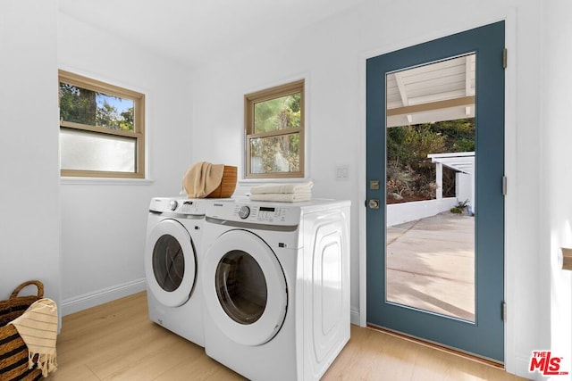 laundry area with plenty of natural light, light hardwood / wood-style floors, and washer and dryer