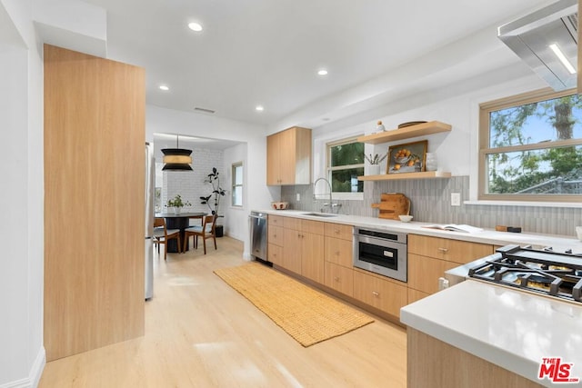 kitchen with sink, appliances with stainless steel finishes, tasteful backsplash, light brown cabinets, and light wood-type flooring