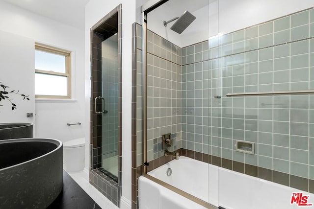 bathroom with toilet and shower / bath combination with glass door