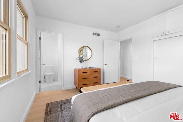 bedroom with light wood-type flooring and ensuite bath