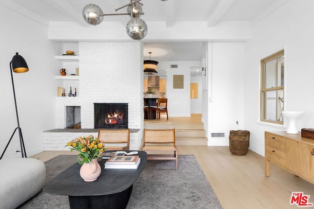 living room with a brick fireplace, light hardwood / wood-style floors, and beamed ceiling