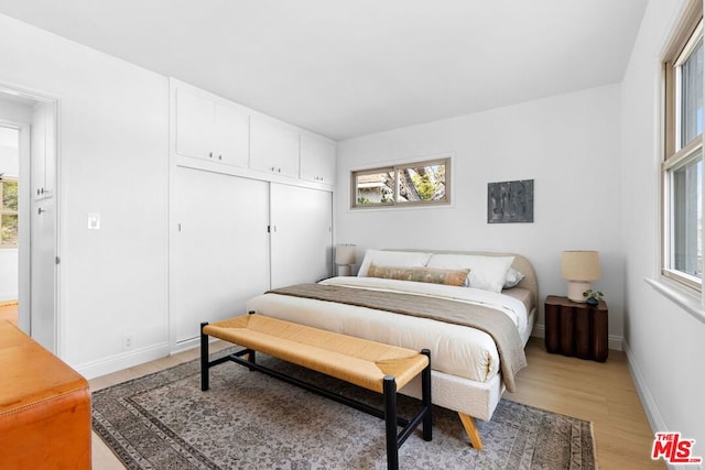 bedroom with light hardwood / wood-style floors and a closet